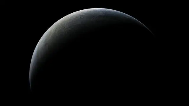 A partial view of a planet emerging from the darkness.